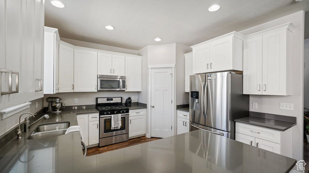 Kitchen featuring appliances with stainless steel finishes, dark countertops, white cabinets, and recessed lighting