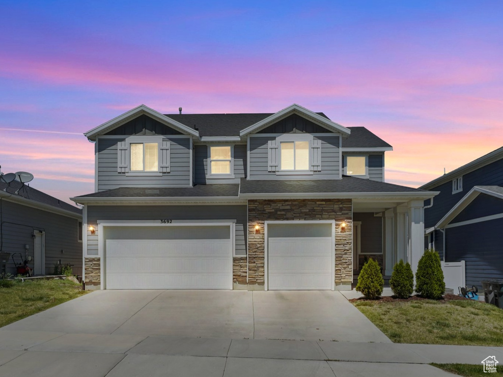 View of front of home featuring stone siding, an attached garage, and driveway