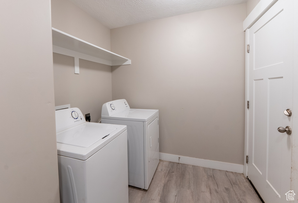 Washroom featuring washing machine and clothes dryer and light wood-style flooring