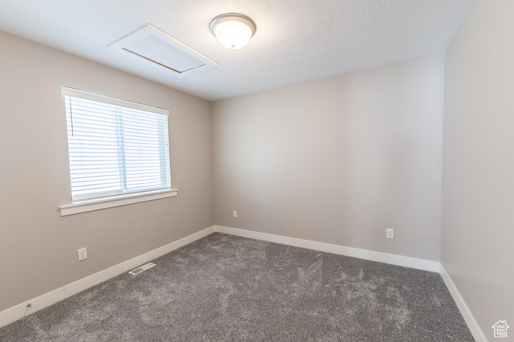Carpeted empty room featuring attic access and baseboards