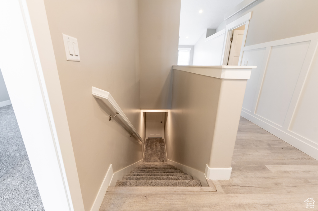 Stairway with wood finished floors and baseboards