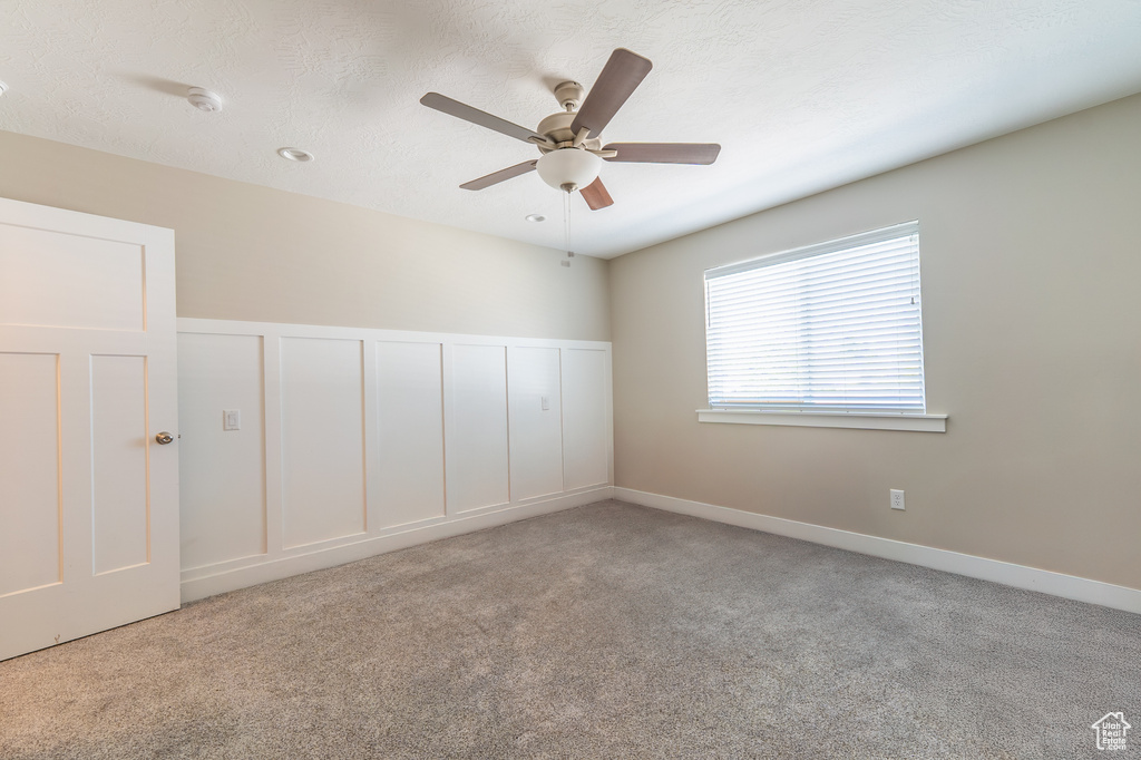 Carpeted empty room featuring a ceiling fan
