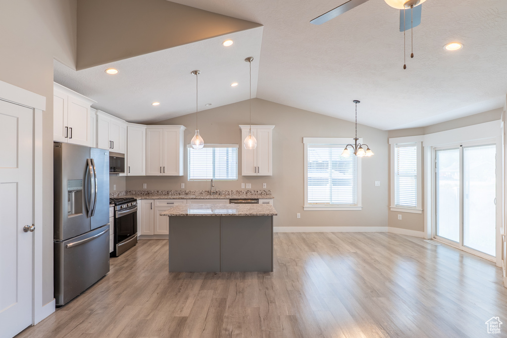 Kitchen with appliances with stainless steel finishes, a kitchen island, vaulted ceiling, white cabinetry, and a ceiling fan