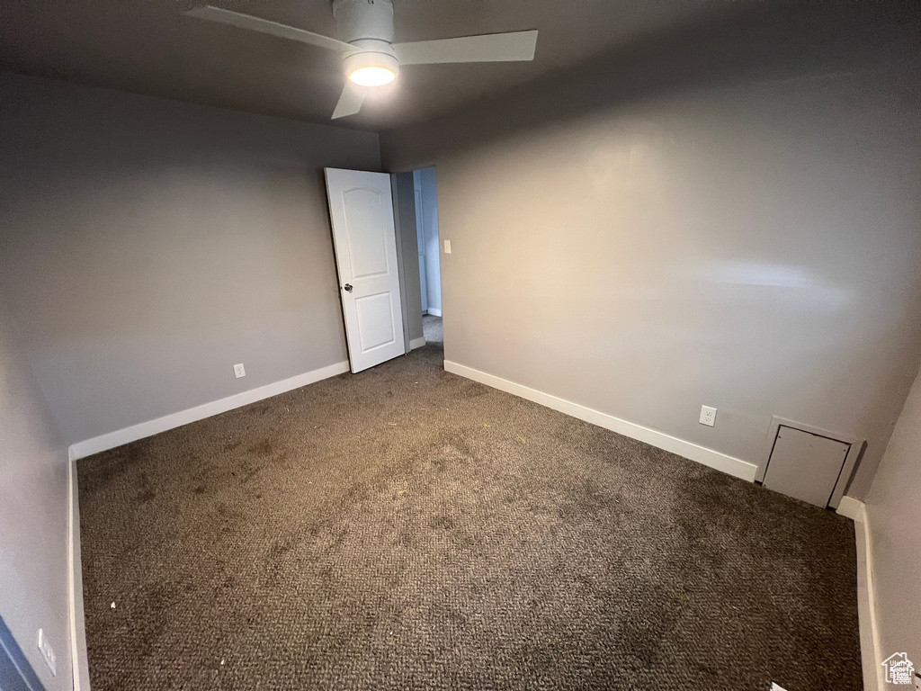 Carpeted empty room featuring a ceiling fan and baseboards