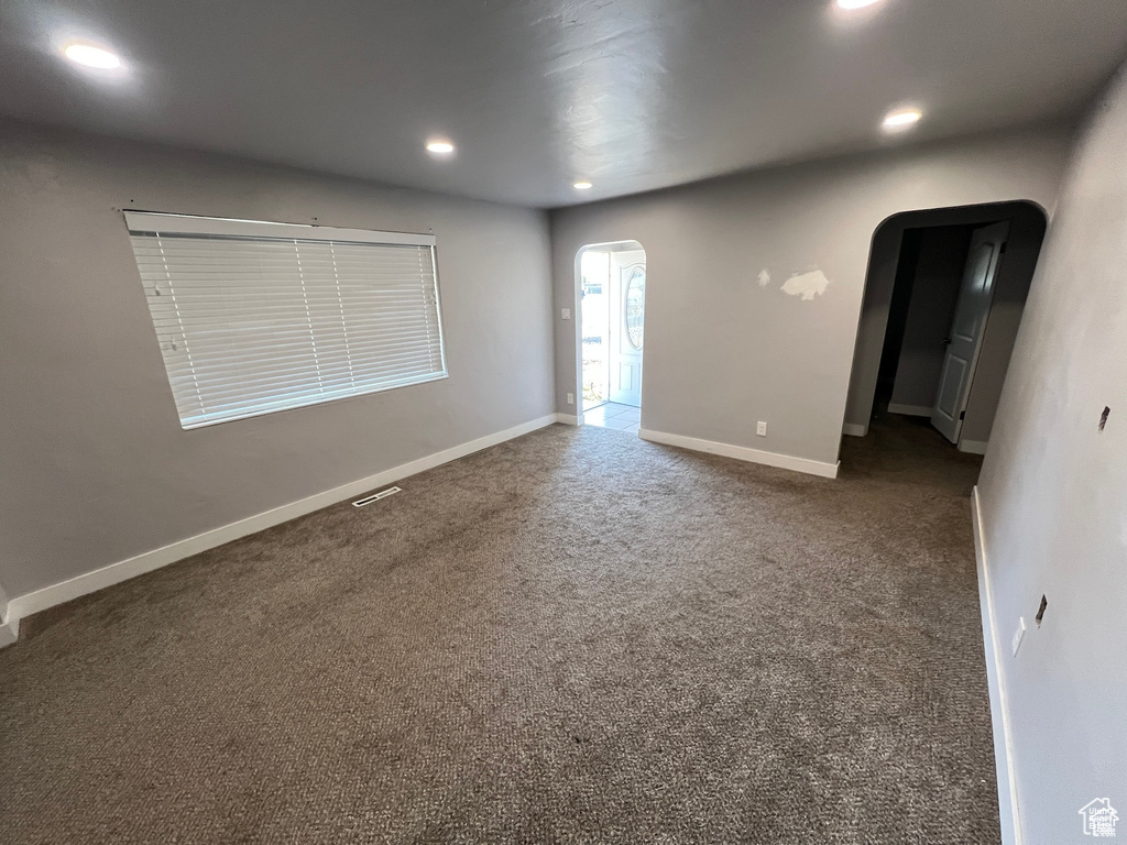 Carpeted spare room with arched walkways and recessed lighting