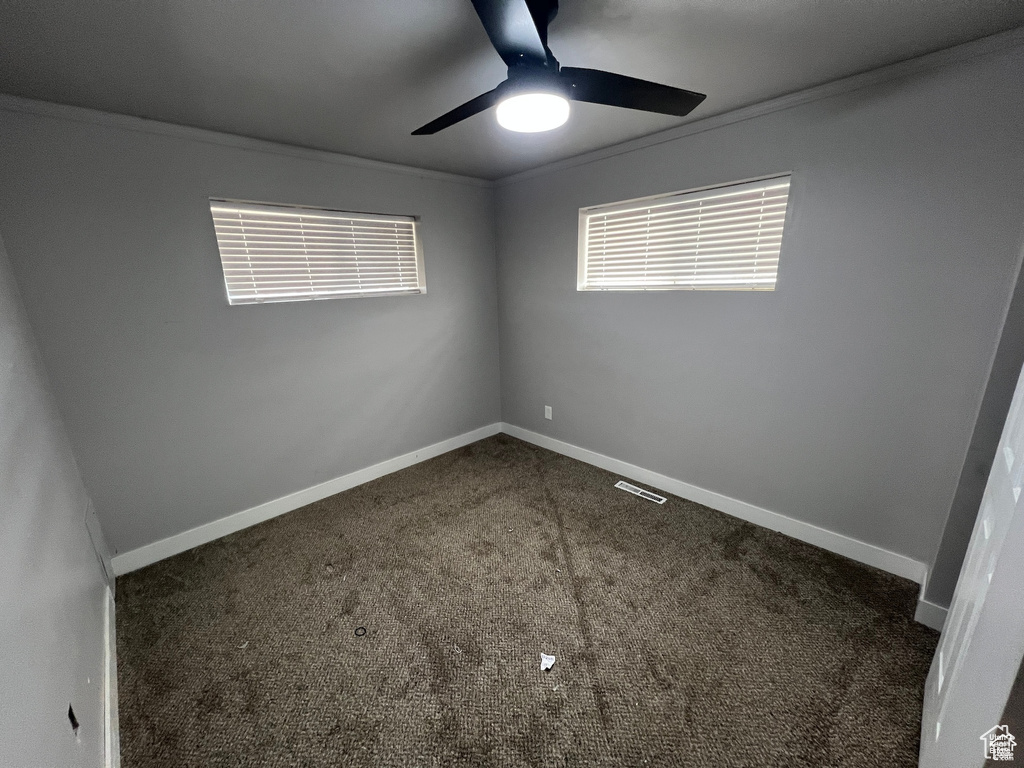 Empty room featuring ceiling fan, carpet flooring, and ornamental molding