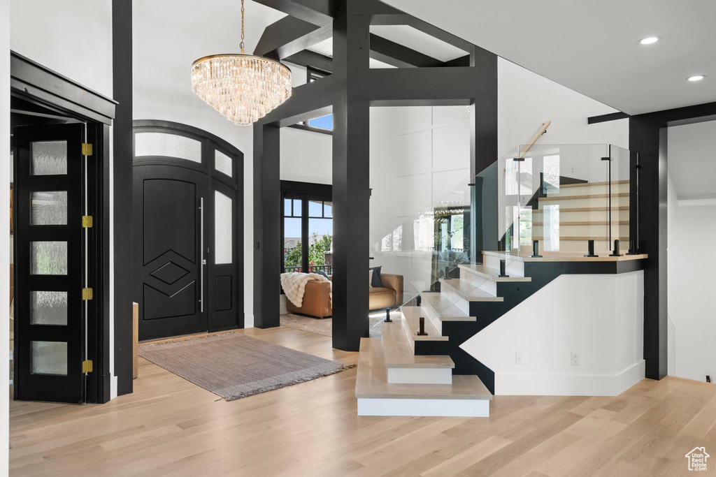 Entrance foyer with a chandelier, wood finished floors, stairs, recessed lighting, and a towering ceiling