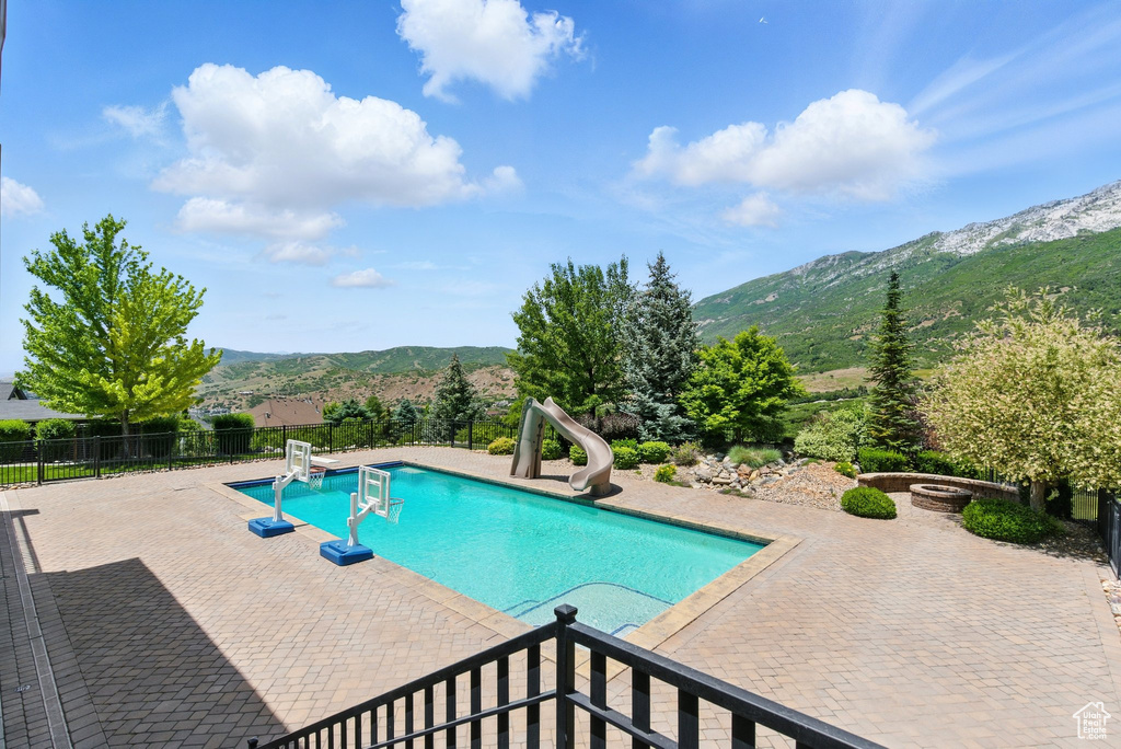View of swimming pool featuring a water slide, a mountain view, and a patio area