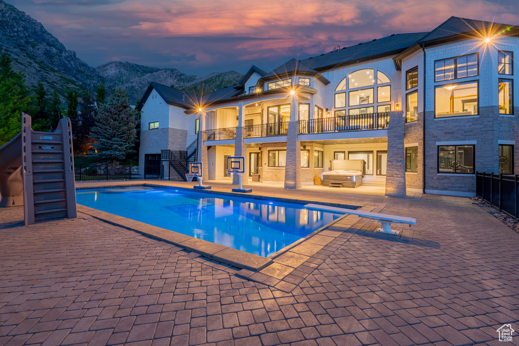Pool at dusk featuring stairs, a diving board, an outdoor pool, and a patio area