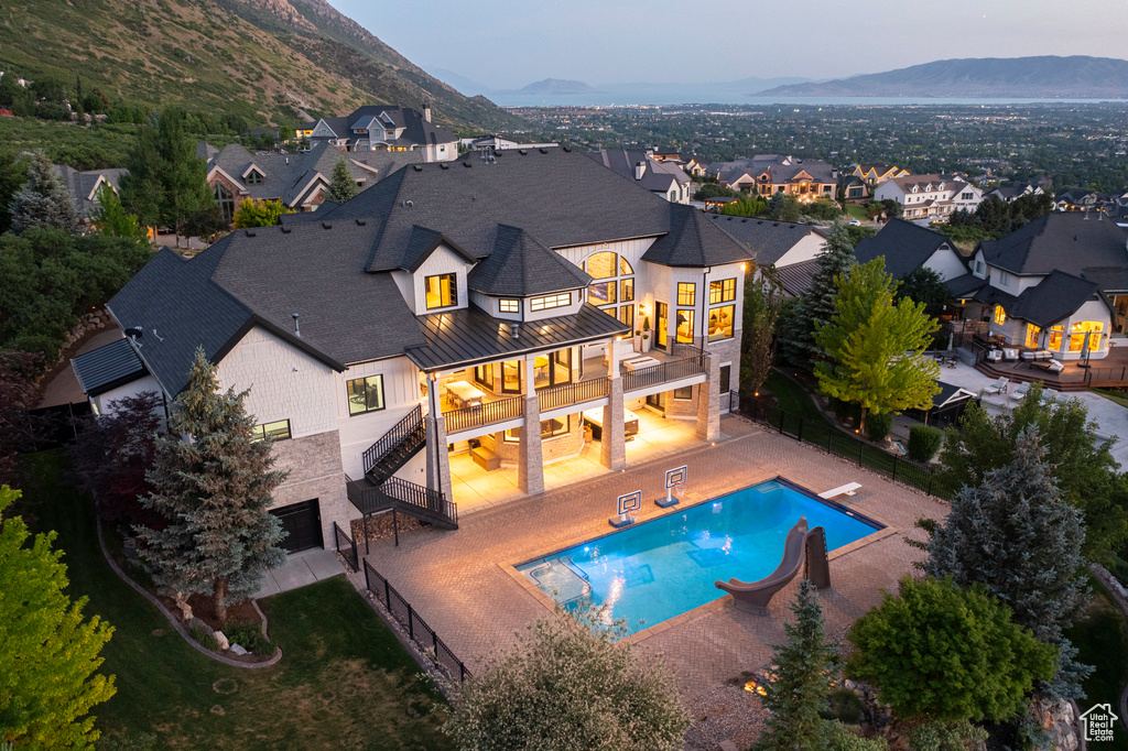 Rear view of property with a balcony, a standing seam roof, a fenced backyard, and a mountain view