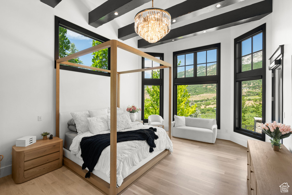 Bedroom featuring a chandelier, light wood-style flooring, a towering ceiling, recessed lighting, and beam ceiling