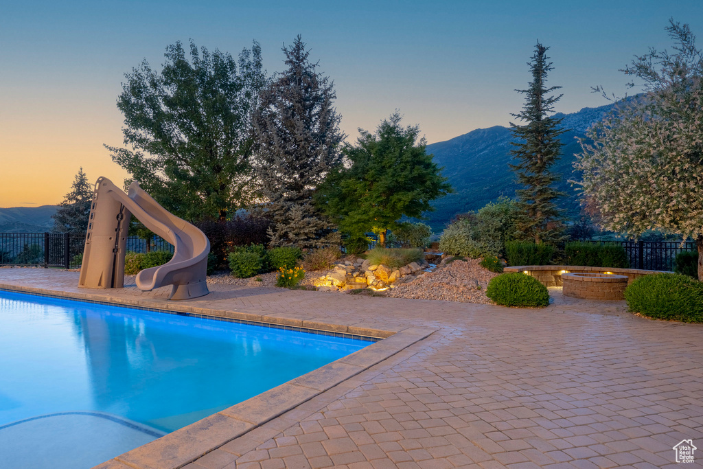 View of pool with a mountain view, a water slide, and a patio