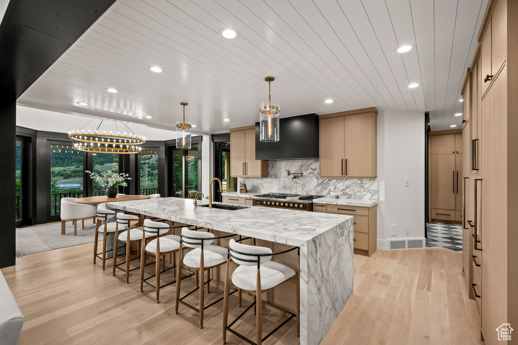 Kitchen with custom range hood, recessed lighting, light wood-type flooring, a spacious island, and backsplash