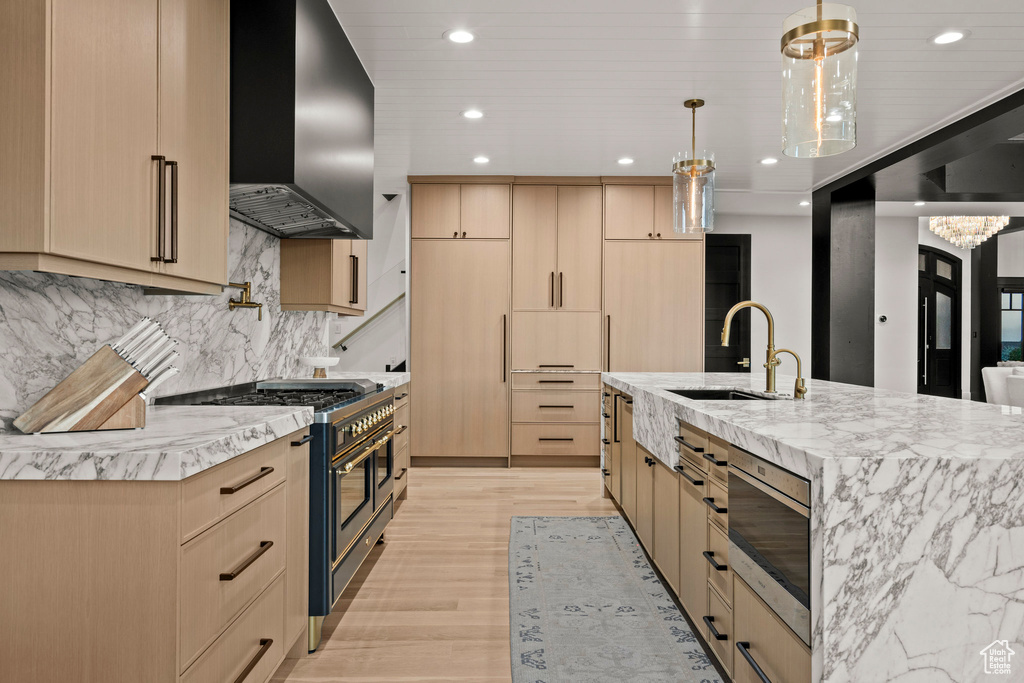 Kitchen featuring wall chimney exhaust hood, double oven range, light brown cabinets, recessed lighting, and stainless steel microwave