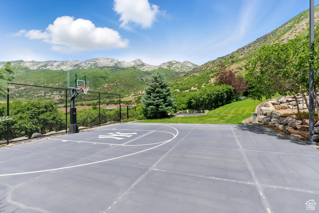 View of sport court featuring a mountain view, community basketball court, and a yard