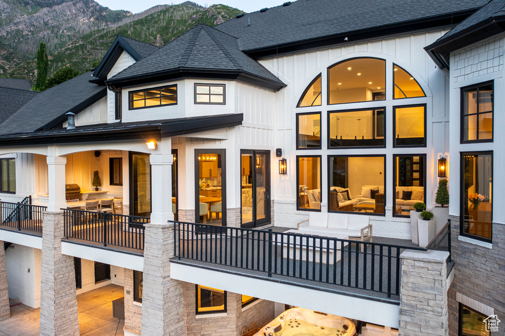 Back of property with a mountain view, a shingled roof, and board and batten siding