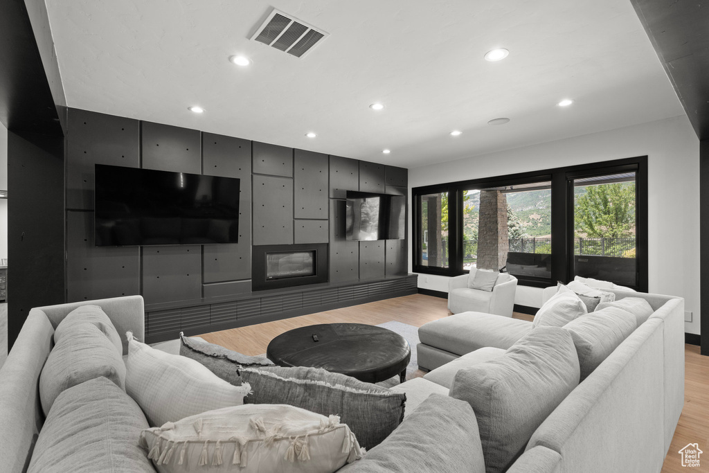 Living area with recessed lighting, light wood-type flooring, and a glass covered fireplace