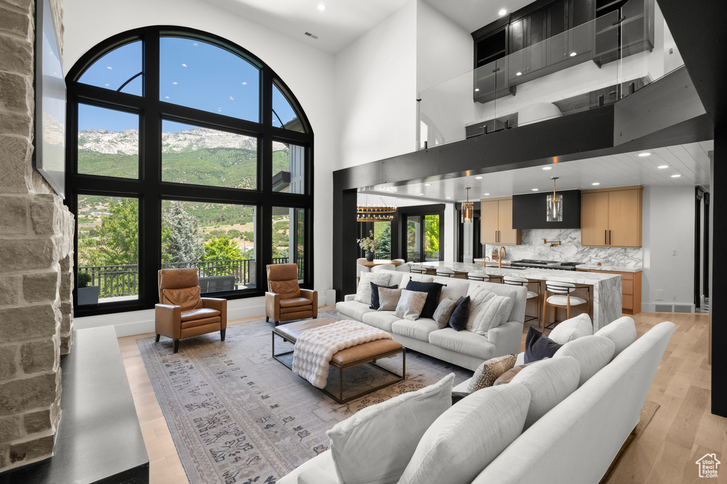 Living area featuring light wood-style floors, recessed lighting, plenty of natural light, and a towering ceiling