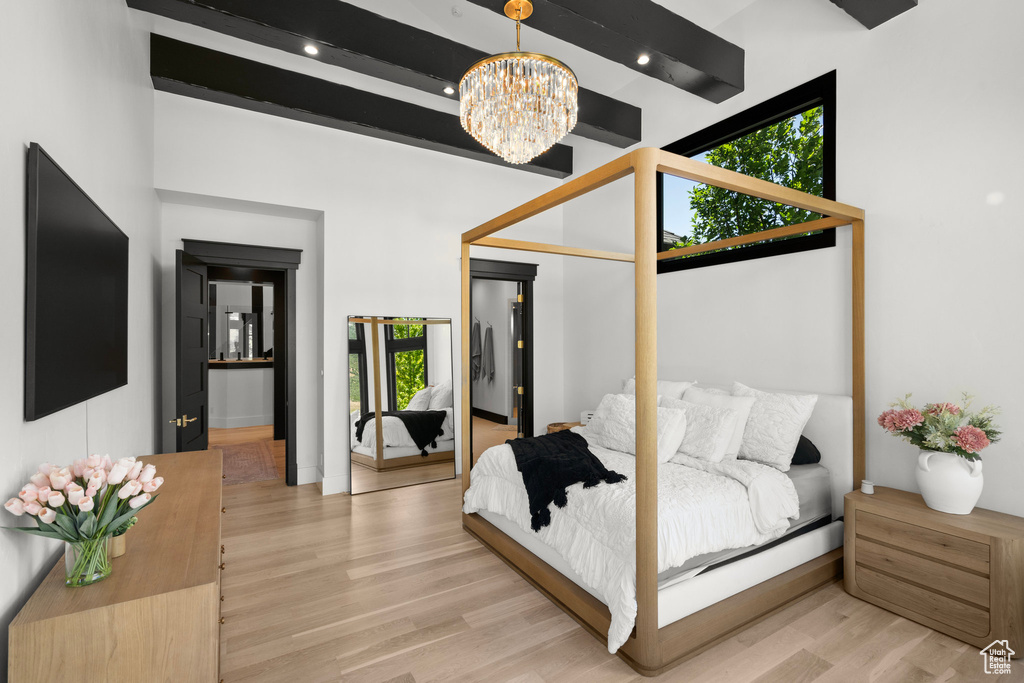 Bedroom with a chandelier, light wood-style floors, and beamed ceiling