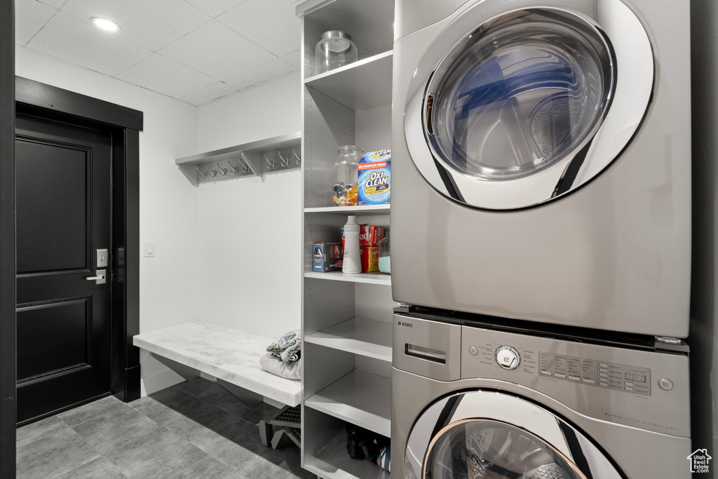 Washroom with stacked washer / drying machine, recessed lighting, and light tile patterned floors