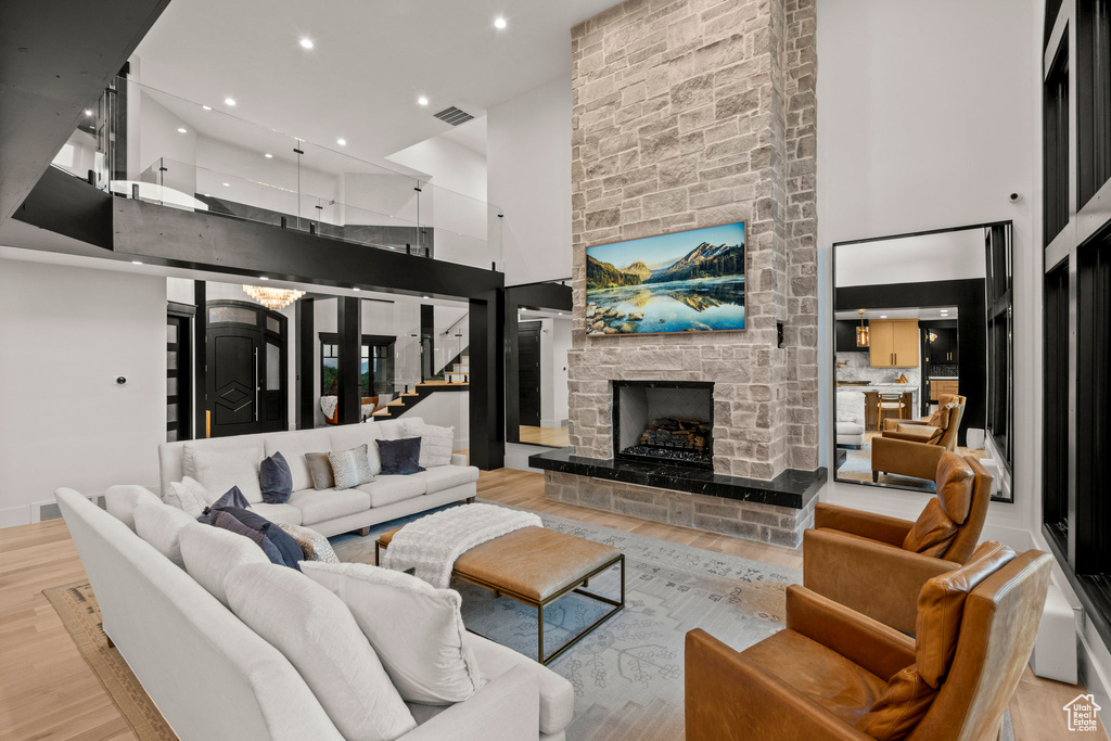 Living area featuring wood finished floors, a high ceiling, a fireplace, stairway, and recessed lighting
