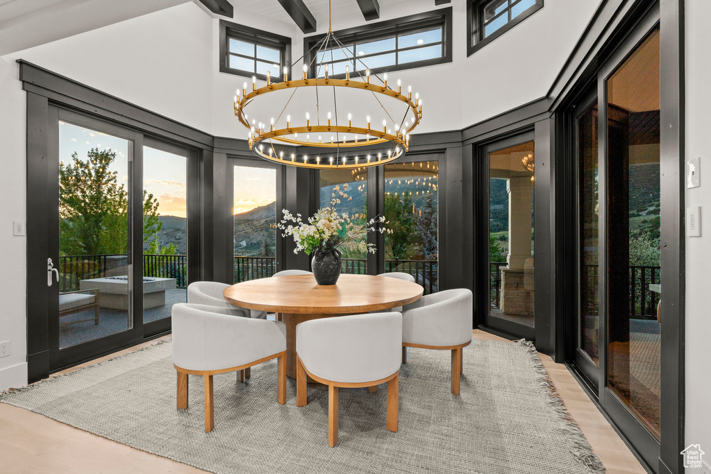 Dining space with a chandelier, a high ceiling, wood finished floors, and french doors