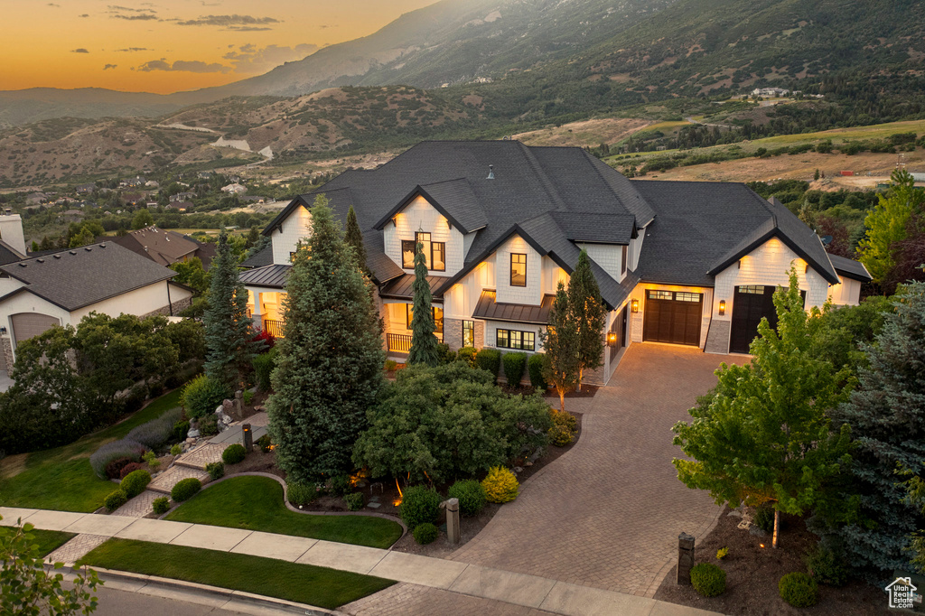 View of front facade featuring an attached garage, a standing seam roof, a mountain view, decorative driveway, and a metal roof