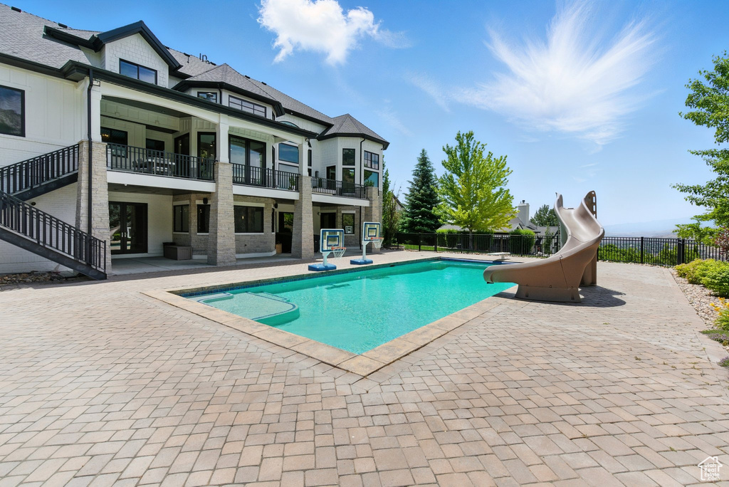 View of pool featuring a water slide, a patio, and stairway