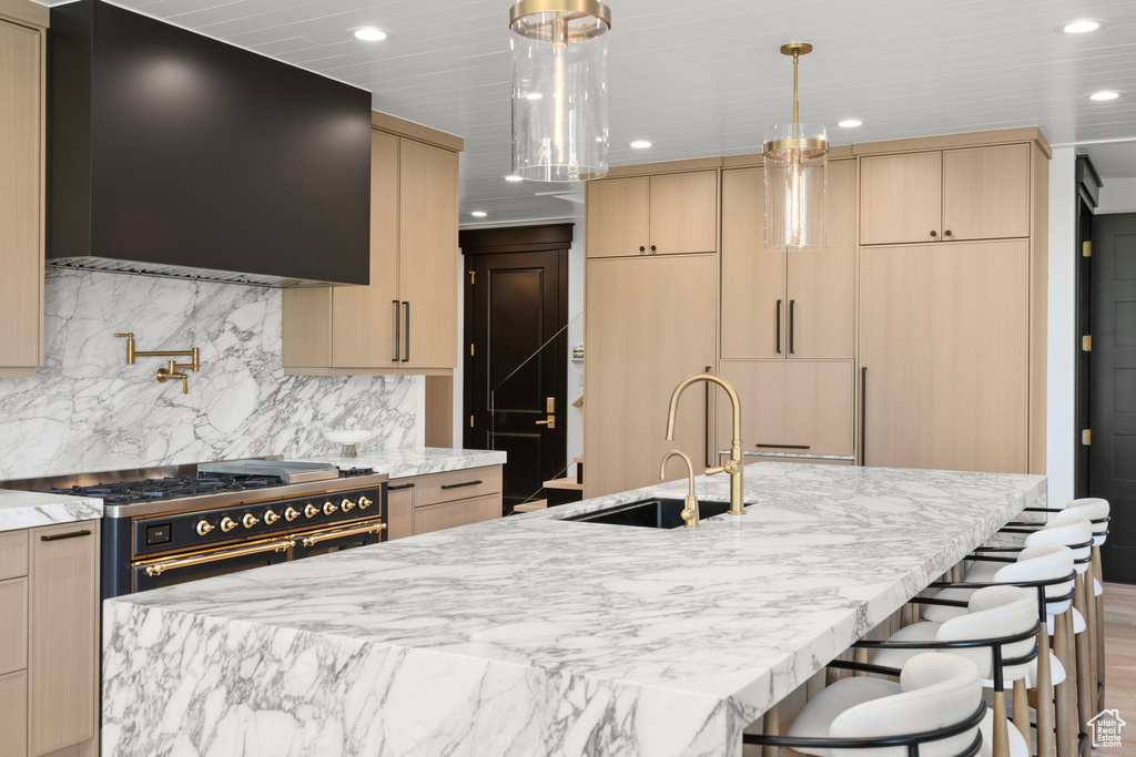 Kitchen with light brown cabinetry, recessed lighting, light stone countertops, extractor fan, and double oven range