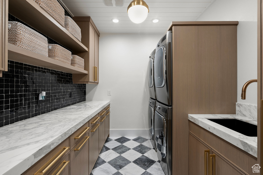 Washroom featuring stacked washing machine and dryer, cabinet space, and recessed lighting