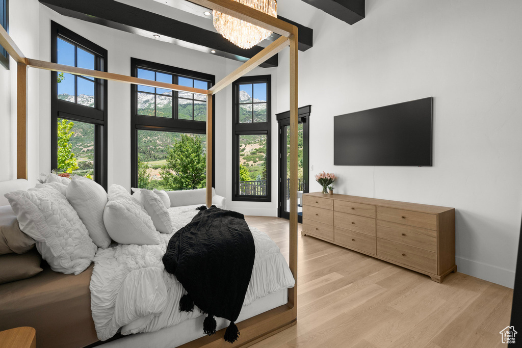 Bedroom with a towering ceiling, light wood-style flooring, and a chandelier