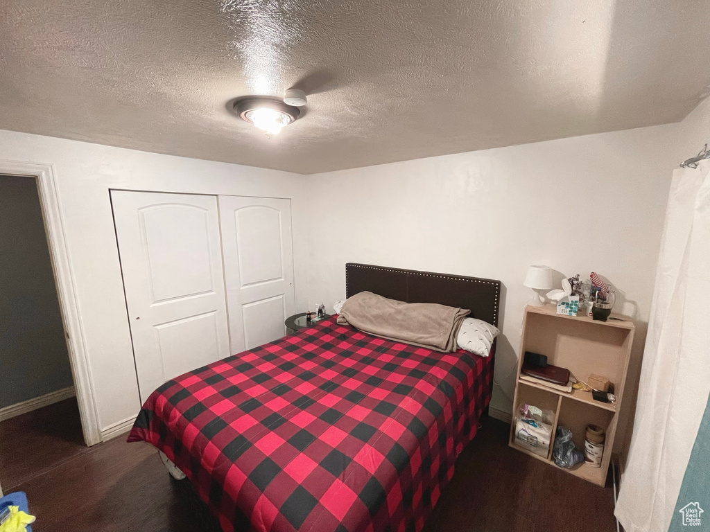 Bedroom featuring a textured ceiling, a closet, and wood finished floors