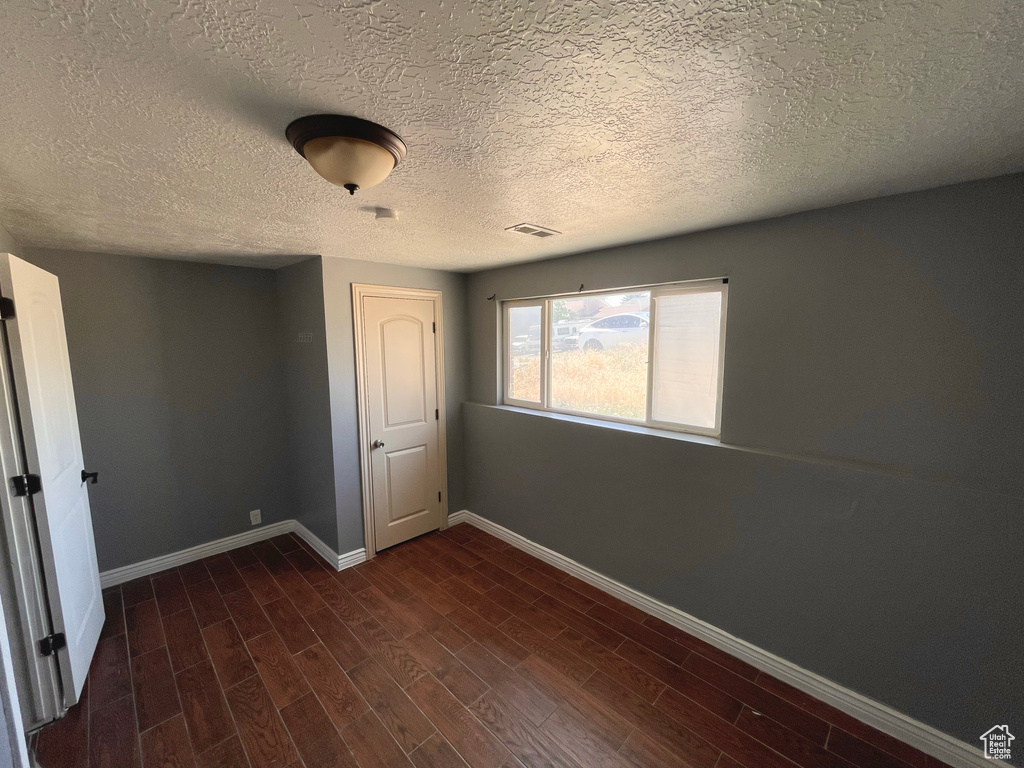 Empty room featuring dark wood finished floors and a textured ceiling