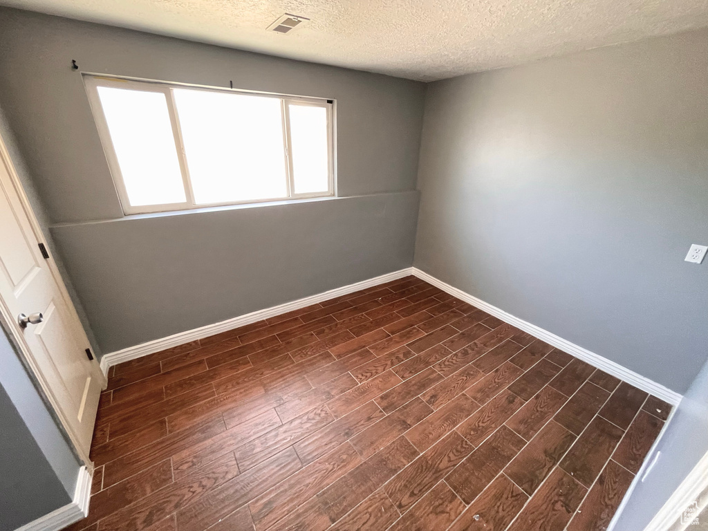 Spare room with dark wood finished floors and a textured ceiling