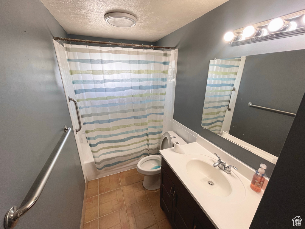 Bathroom with a textured ceiling, vanity, and shower / bathtub combination with curtain