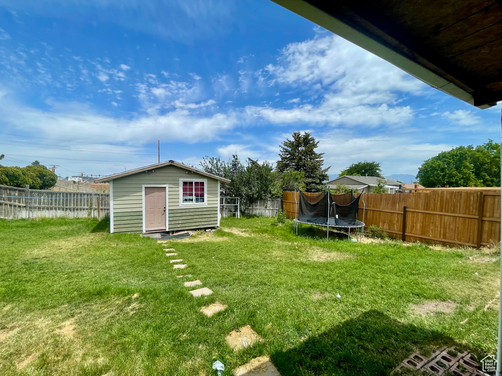 Fenced backyard with a trampoline and an outbuilding