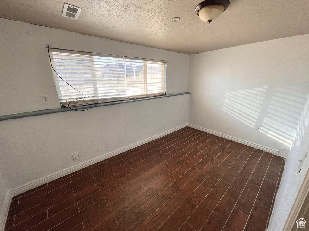 Empty room featuring dark wood-style floors and a textured ceiling