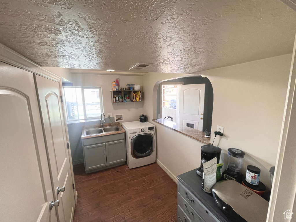 Laundry room featuring washer / dryer, cabinet space, dark wood finished floors, arched walkways, and a textured ceiling