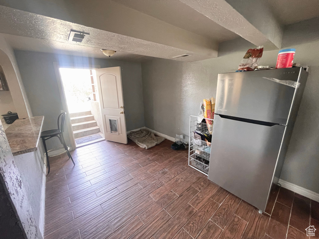 Kitchen with freestanding refrigerator, dark wood-style flooring, and a textured ceiling