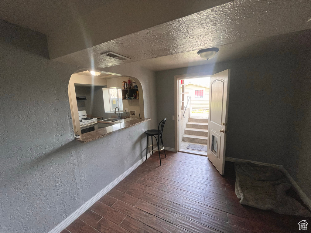 Dining room with a textured wall, arched walkways, dark wood finished floors, and a textured ceiling