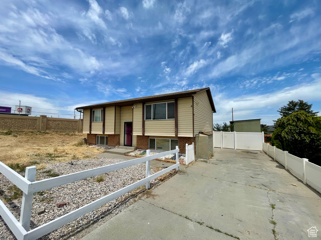 Bi-level home with concrete driveway, a fenced front yard, and brick siding