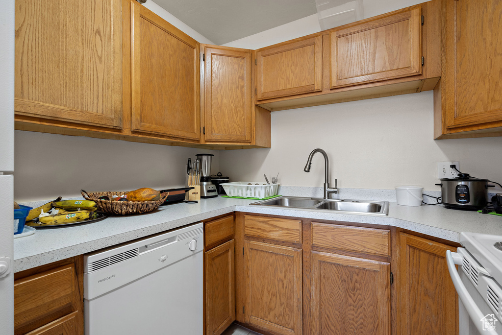 Kitchen with dishwasher, light countertops, range, and brown cabinetry