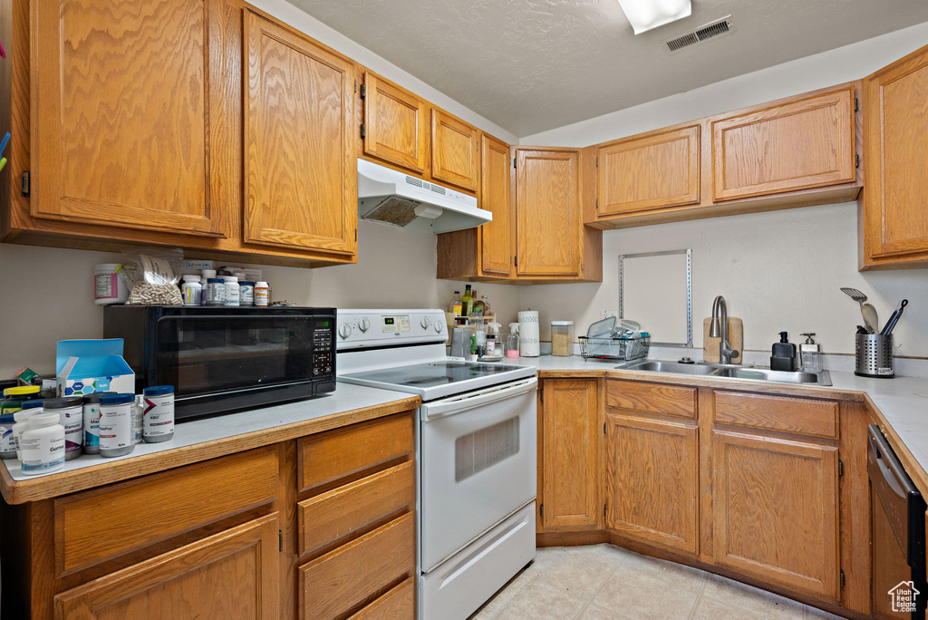 Kitchen featuring white electric stove, under cabinet range hood, stainless steel dishwasher, light countertops, and light tile patterned floors