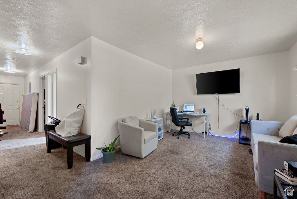Living area with carpet floors, a desk, and a textured ceiling