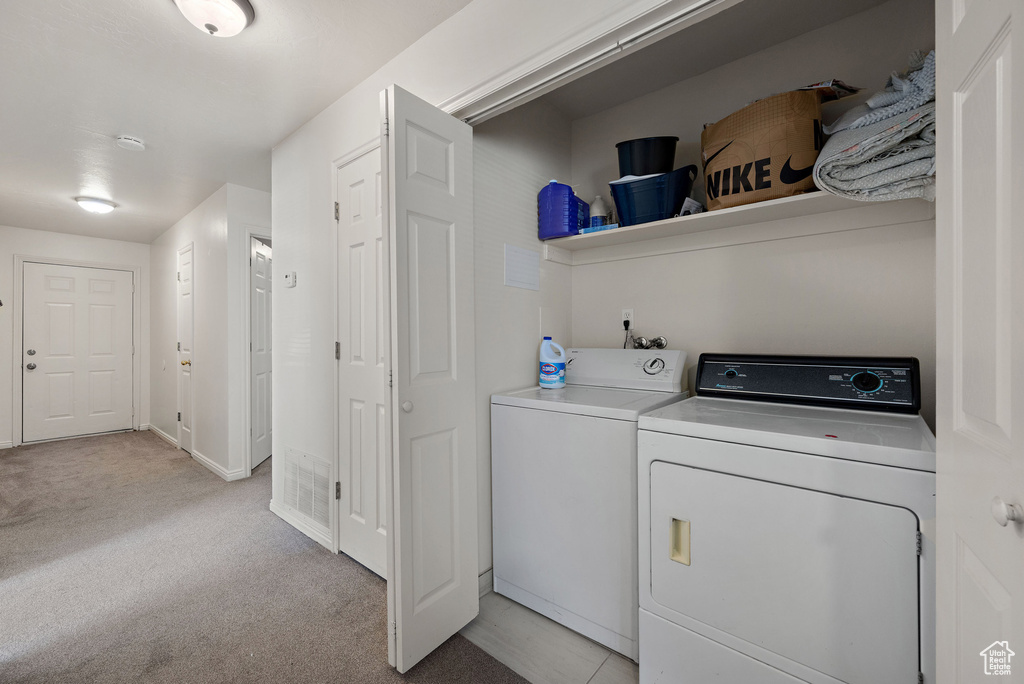 Laundry area with separate washer and dryer and light colored carpet