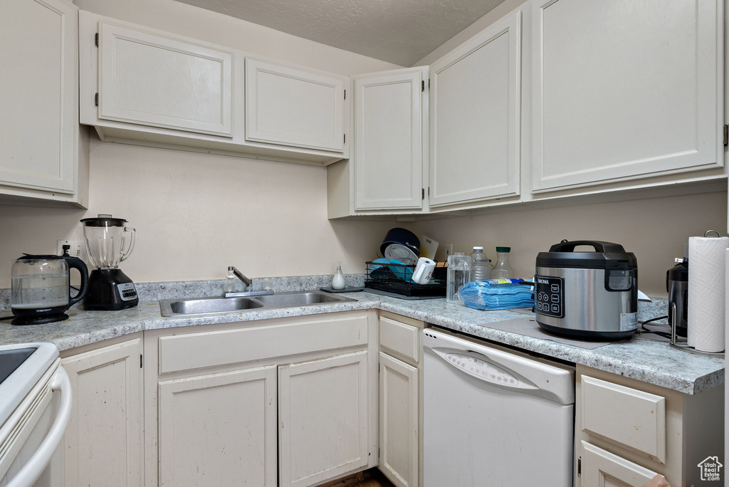 Kitchen with dishwasher, light countertops, and white cabinets