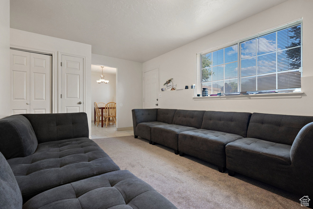 Carpeted living area featuring a chandelier and baseboards