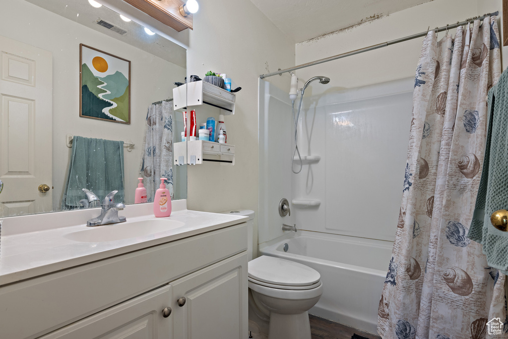 Bathroom with vanity, shower / tub combo, and wood finished floors