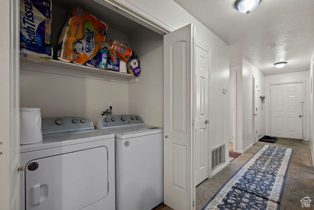 Laundry room featuring washer and clothes dryer and light colored carpet