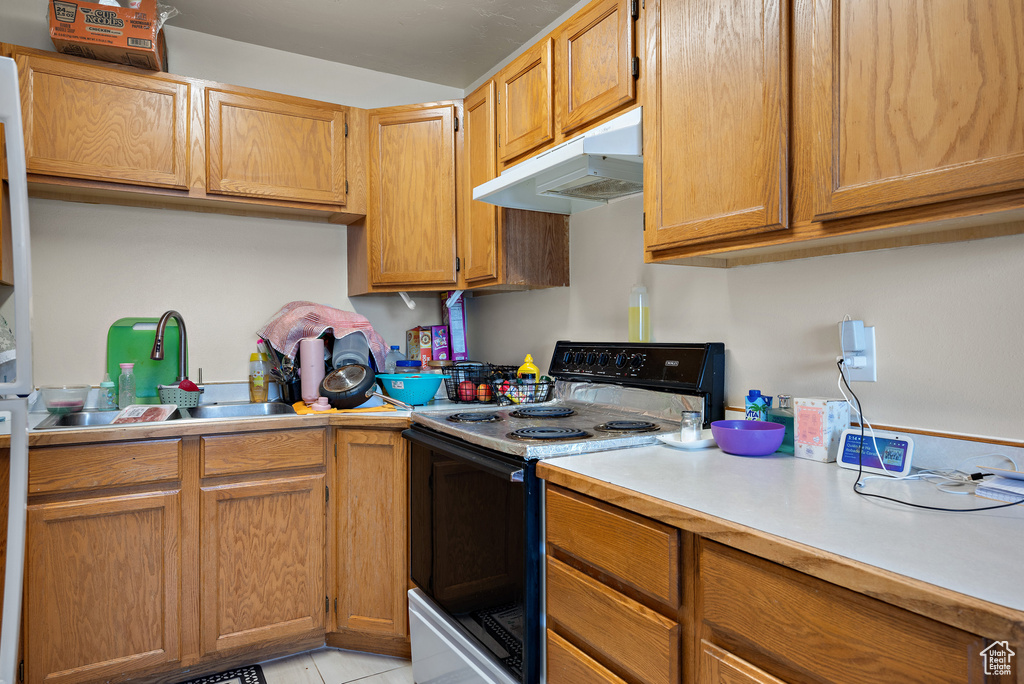Kitchen featuring electric stove, under cabinet range hood, light countertops, and light tile patterned floors